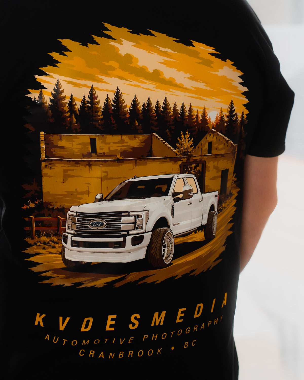 Back graphic of KVDESMEDIA x Aspect T-Shirt featuring a white Ford F-350 in front of a rustic building at sunset